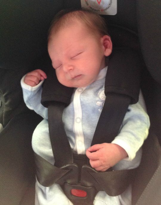 Asleep in his car seat.